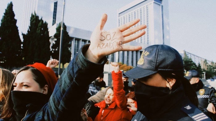 A woman wearing a face mask holds her hand up at a protest